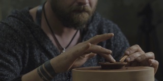 一名陶工用一把木刀从宜兴的陶土中取出壶盖上多余的陶土。茶道用手工陶壶。4 k的视频。59.94帧/秒
