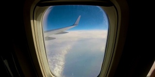 飞机飞过云层，透过窗户望向机翼的一架客机