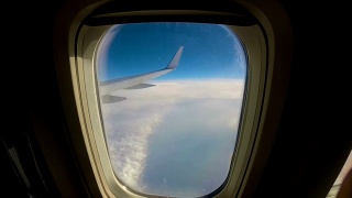 飞机飞过云层，透过窗户望向机翼的一架客机视频素材模板下载