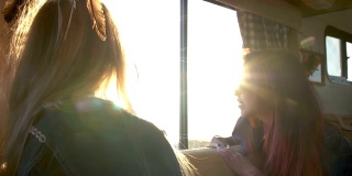 两个女孩在夕阳的余晖中望着汽车拖车的窗外