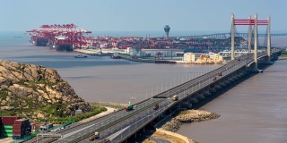 4K时间推移:鸟瞰图工业港口与货轮和集装箱卡车在桥上。