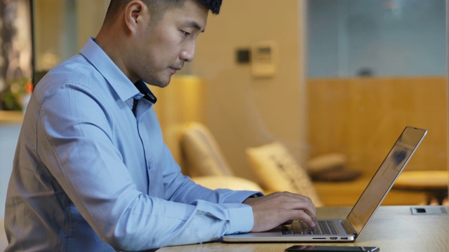 年轻的亚洲商人用笔记本电脑工作