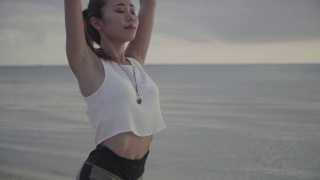 一名千禧年妇女在户外沙滩上练习瑜伽的中镜头视频素材模板下载