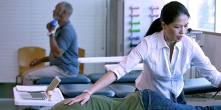 女性物理治疗师在物理治疗期间对一个退伍军人的腿进行治疗