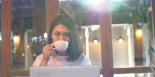 女性自由职业者用她的笔记本电脑工作，在咖啡馆喝咖啡，慢镜头