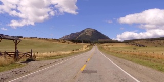驱动板。乡村公路上的汽车，山脉，山谷- POV -视角前-挡风玻璃。的一天。