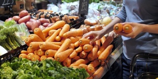 年轻女子购物新鲜蔬菜选择水果在市场。健康的生活方式