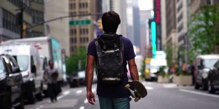 带着滑板走在纽约街头的潮人。自信的千禧一代纽约人。