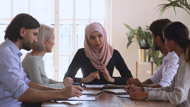 亚洲穆斯林女性公司领导在团队会议上讨论文书工作