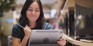 兴奋快乐的亚洲女人看着数字平板电脑兴奋地表达获胜的姿态