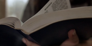女人读着一本书，翻着书页，圣经，靠近