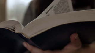 女人读着一本书，翻着书页，圣经，靠近视频素材模板下载