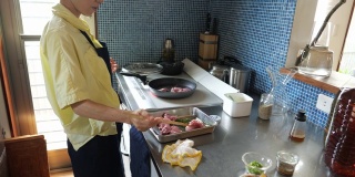 妇女烹饪猪肉在IH烹饪加热器