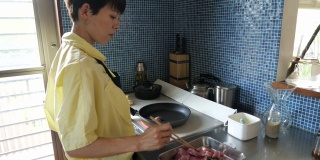妇女烹饪猪肉在IH烹饪加热器