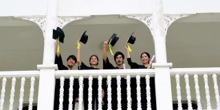 一群快乐的学生在毕业典礼上举起手臂。