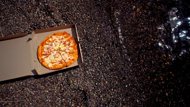 在卵石滩上放着披萨的纸箱。