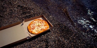 在卵石滩上放着披萨的纸箱。