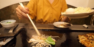 一个年轻女子在日式餐馆里用煎锅煮蔬菜
