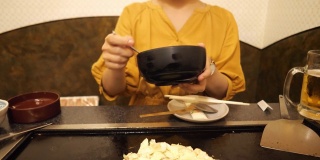在日式餐厅里，年轻女子在煎锅上做御膳烧