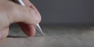 一个男人用圆珠笔在白纸上写东西