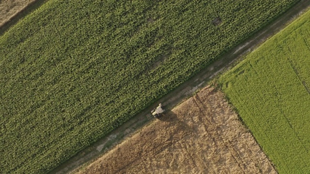 空中农民在一辆停在田地边上的拖拉机旁使用平板电脑。