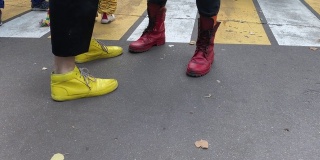 小丑们的腿和脚穿着五颜六色有趣的黄和红靴子，在柏油路上互相玩耍