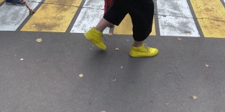 小丑们的腿和脚穿着五颜六色有趣的黄和红靴子，在柏油路上互相玩耍