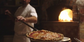 披萨师傅将新鲜出炉的带皮那不勒斯披萨放在盘子里
