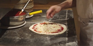 厨师在披萨上撒上奶酪
