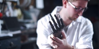 一位科学家工程师正在测试一个电子仿生假肢。他移动机械手臂的塑料手指。现代修复技术。科学家手中的控制论之手