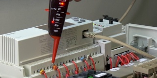 工厂工人的手检查电子设备的触点电压指示器。
