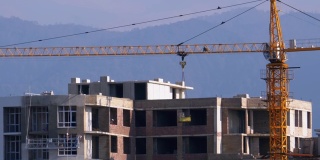 建筑工地上的塔式起重机在高层建筑中吊装重物