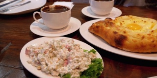 格鲁吉亚餐厅里的阿贾利安·哈切布里(Adjarian Khachapuri)，旁边是沙拉、煎蛋卷和咖啡