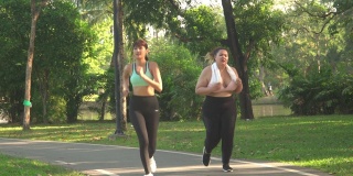 以下正面视图:女性身材高大的运动员和她的朋友跑步。她很努力，但她继续跑