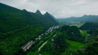 鸟瞰喀斯特山峰森林(万峰林)中的村庄和稻田，贵州，中国。视频素材模板下载