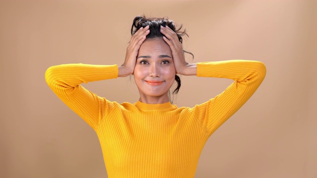 4K中拍摄的快乐年轻美丽的亚洲女人的肖像女孩的脸和身体穿着黄色长袖衬衫都在微笑孤立的背景。人的面部和身体具有快乐放松的情绪概念。
