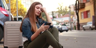 疲惫的女人坐在人行道上用手机找出租车
