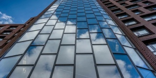 镜面反射在摩天大楼的玻璃表面，蓝天与云彩