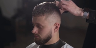 英俊的理发师为男顾客理发，打造时尚的发型。理发师在理发店为顾客服务