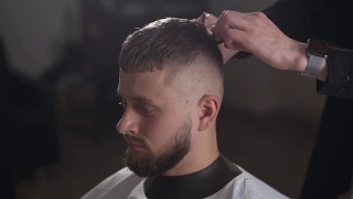 英俊的理发师为男顾客理发，打造时尚的发型。理发师在理发店为顾客服务视频素材模板下载