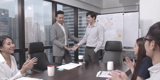 4K分辨率的视频亚洲合作伙伴会议和握手与快乐亚洲业务团队在室内现代办公室庆祝鼓掌