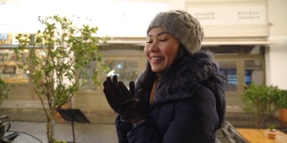 亚洲女人感到寒冷，在圣诞之夜在街上搓着冰冷的手