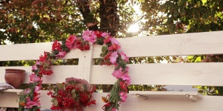 白色的篱笆上，挂着一个大的粉红色花和荚蒾花环