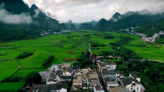 鸟瞰喀斯特山峰森林(万峰林)中的村庄和稻田，贵州，中国。视频素材模板下载