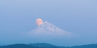 一轮满月从白雪覆盖的山峰后面升起。俄勒冈州胡德山。