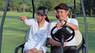 坐在高尔夫球车上的夫妇在高尔夫球场上。视频素材模板下载