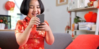 慢镜头，快乐的亚洲女孩用智能手机和她的家人视频通话，中国新年庆祝