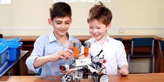 两个兄弟的孩子在学校的机器人课上玩机器人玩具，室内
