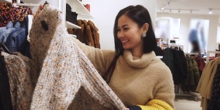 亚洲女人在商场购物，买圣诞礼物，买衣服(所有品牌都模糊了)