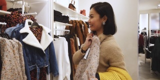 亚洲女人在商场购物，买圣诞礼物，买衣服(所有品牌都模糊了)